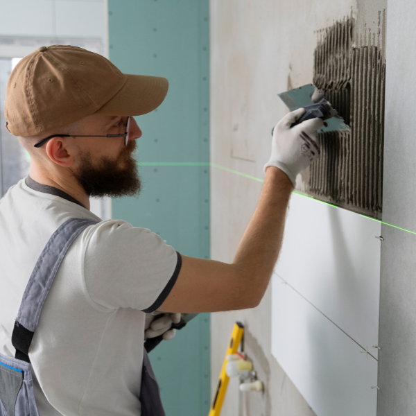 photo d'un carreleur qui enduit un mur pour poser le carrelage